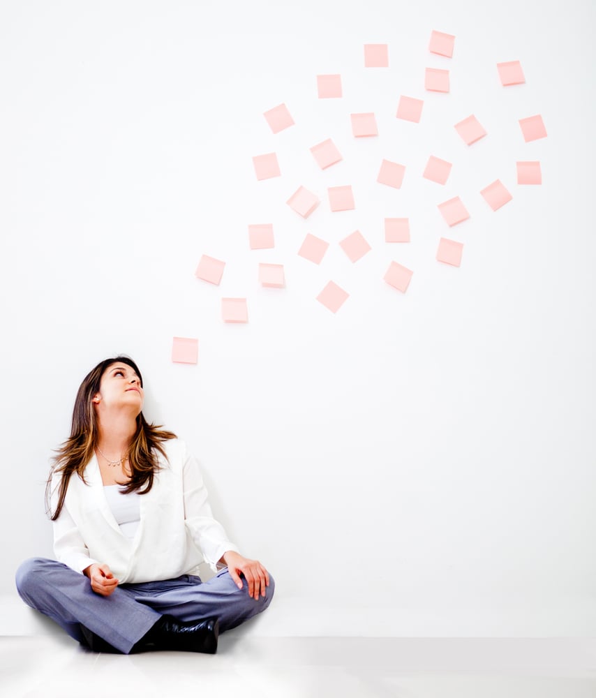 Thoughtful business woman with a bubble of post its - isolated over white